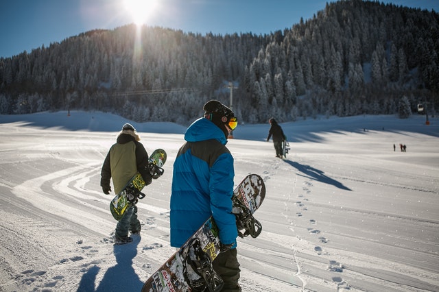 People carrying snowboards on a trail in one of the best ski resorts in Europe for families.