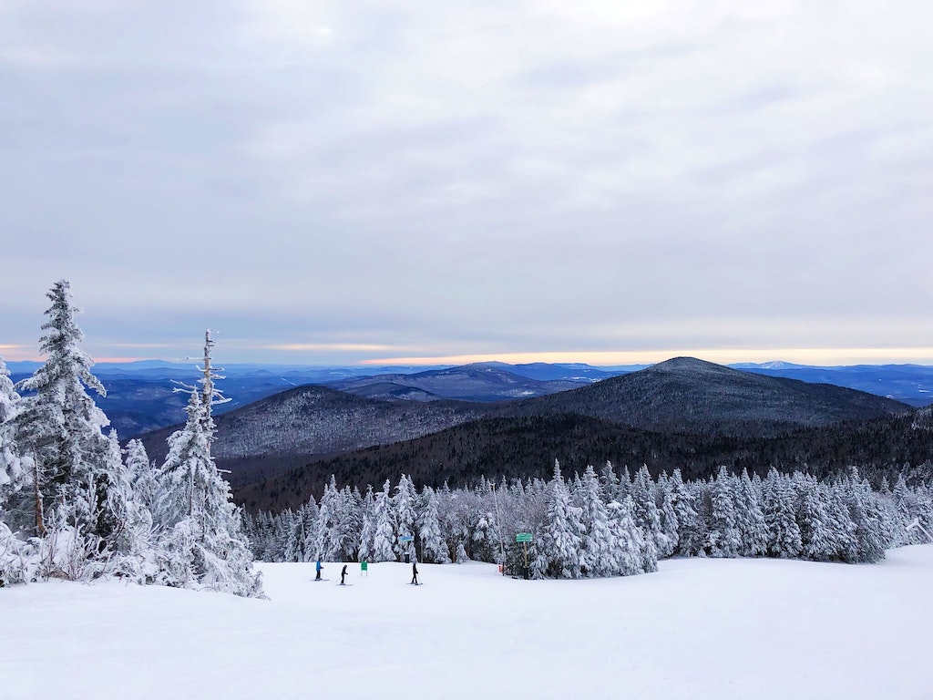 Beautiful view at the slopes of the Killington Mountain Resort with a fresh patch of snow and people skiing in the distance.