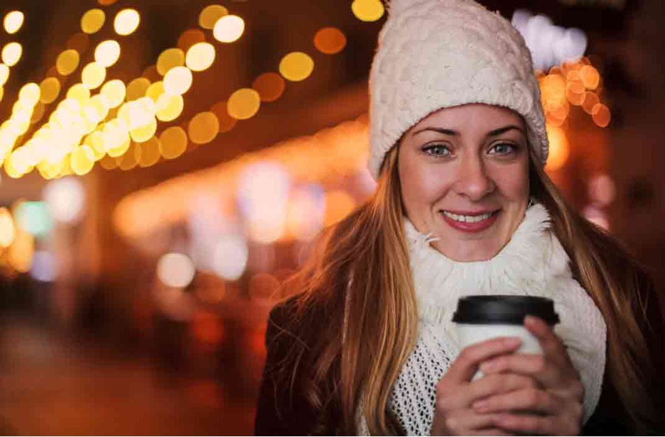 Smiling woman wearing winter outfit with hot drink 