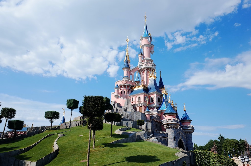 A pink Disney Castle with blue roofing