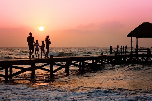 A family standing near the water while the sun goes down